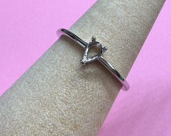 May include: A silver ring with a teardrop-shaped setting for a gemstone.