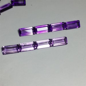 May include: A group of purple amethyst gemstones cut in a rectangular shape with a faceted finish.