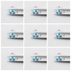 May include: Nine oval-shaped gemstones of varying sizes, ranging from 4mm to 12mm, are displayed in tweezers. The gemstones are a light blue color.