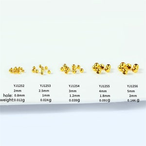 May include: Five rows of gold-colored metal beads of varying sizes, with the bead size increasing from left to right. Each row is labeled with a product code, size in millimeters, hole size in millimeters, and weight in grams.
