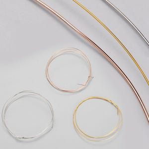 May include: An overhead shot shows metal wires and wire circles. The wires are silver, gold, and copper. Several wire circles are also visible, showcasing the different colours and textures of the metal.
