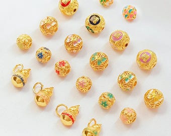 May include: An assortment of gold-colored beads and charms. The beads feature intricate floral and geometric designs, with some displaying Chinese characters in red, black, and pink. Several gourd-shaped charms are also present, adorned with colorful enamel.