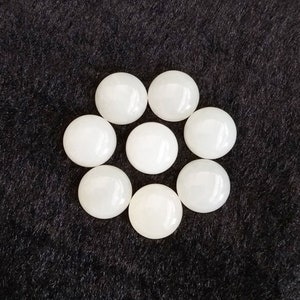 May include: Eight white round smooth stones arranged in a circle on a black background.