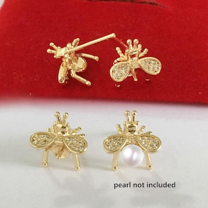 May include: Gold-toned bee-shaped earrings with rhinestone accents. One pair is a stud design, and the other is a dangle style. The text "pearl not included" is visible.