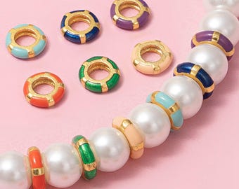 May include: A collection of colorful enamel and gold-tone beads. The beads are in various colors, including blue, purple, green, orange, and peach. The beads are round with a gold-tone center and are interspersed with large white pearl beads.