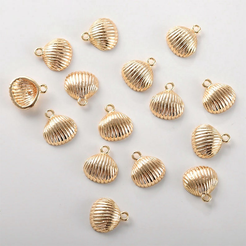 May include: A collection of 16 gold-coloured seashell charms with a loop for attaching to jewellery or other crafts.