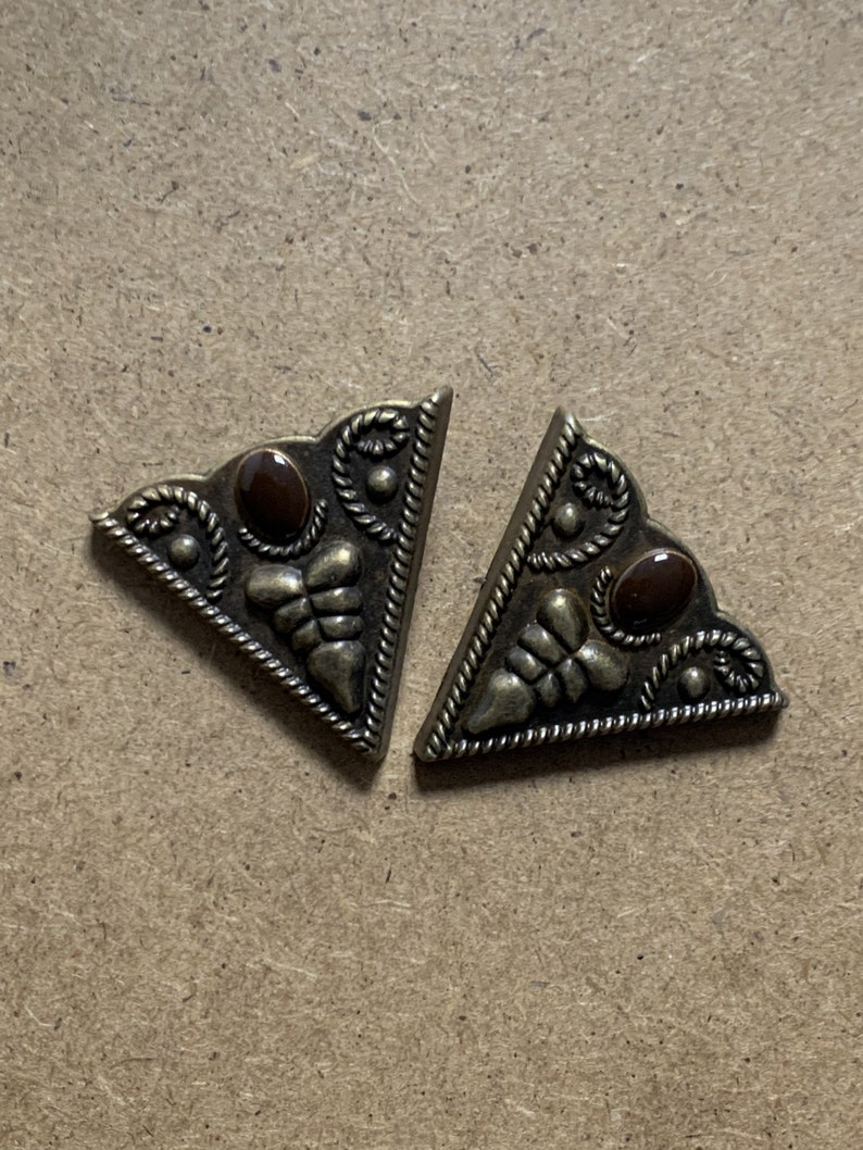 May include: Two gold-tone metal triangle-shaped corner protectors with a brown stone accent in the center of each.