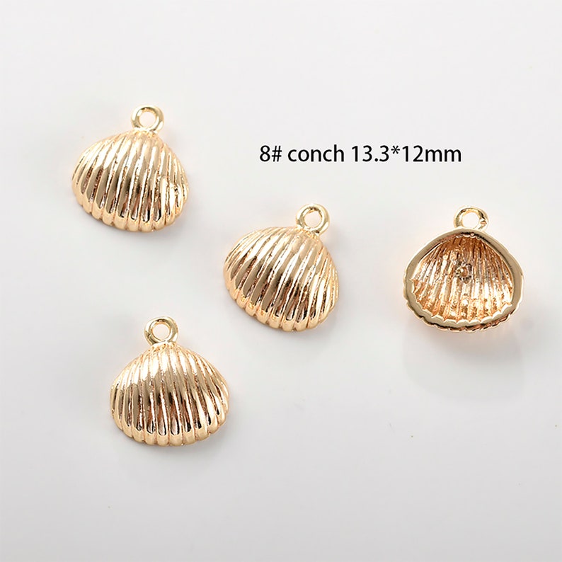 May include: Four gold-coloured seashell charms with a hole for attaching to jewellery. Each charm is approximately 1.3 cm by 1.2 cm.