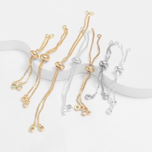 May include: A collection of adjustable slider bracelets featuring thin box chains in gold and silver tones. Each bracelet includes a sliding bead mechanism and ends with small, clear, round faceted stones set in matching metal bezels.