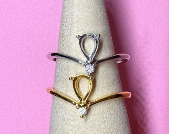 May include: Three silver and gold rings with a V-shaped band and a teardrop-shaped setting with a small diamond accent.