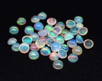 Può includere: Un mucchio di cabochon di opale bianco iridescente, ognuno con un motivo di colore leggermente diverso.