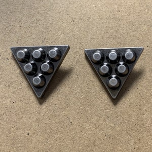May include: Two silver triangle-shaped metal embellishments with a raised design of seven circles.