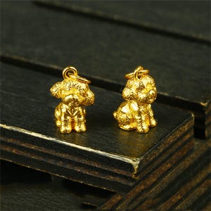 May include: Two gold-colored poodle dog charms. The charms are detailed and have a shiny finish.