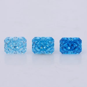 May include: Three rectangular-shaped gemstones, each with a different shade of blue. The gemstones are arranged in a row from left to right, with the lightest blue on the left and the darkest blue on the right.