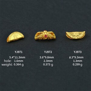 May include: Three gold-colored metal charms with intricate designs. The charm on the left is a half-circle with a raised design. The charm in the middle is a more complex design with a red stone in the center. The charm on the right is a half-circle with a raised design. The charms are labeled with their size and weight in millimeters and grams.