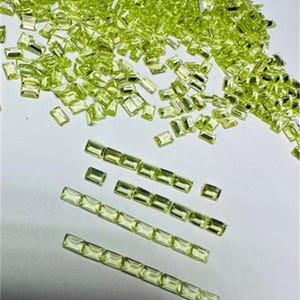 Puede incluir: Una gran cantidad de piedras preciosas rectangulares de color verde claro, algunas de las cuales están dispuestas en filas.