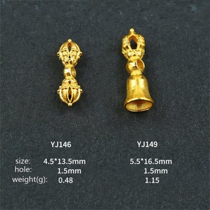 May include: Two gold-colored metal pendants with intricate designs. The pendant on the left is a double-sided design with a small hole in the middle. The pendant on the right is a bell-shaped design with a small hole at the top. The pendants are labeled with their sizes and weights in millimeters and grams.