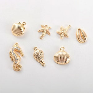 May include: Gold-toned metal charms with a nautical theme. The charms include a seashell, a starfish, a seahorse, and a conch shell.
