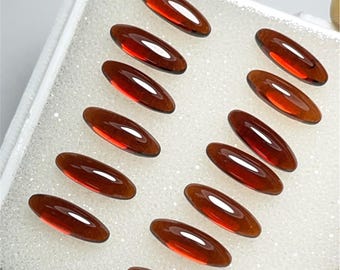 Può includere: Una collezione di 12 pietre preziose ovali di colore rosso in una scatola bianca foderata di schiuma. Le pietre preziose sono disposte in file, con tre pietre preziose in ogni fila.