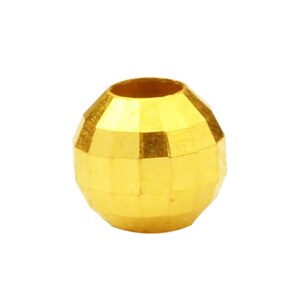 May include: A gold-colored round bead with a faceted design. The bead has a hole in the center for stringing.