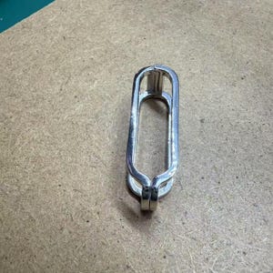 May include: A silver metal ring with a rounded rectangular shape. The ring is open on one side and has a smooth, polished finish.