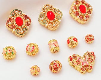 May include: A collection of gold-colored beads and charms with red, pink, and white accents. The assortment includes various shapes, such as floral, round, and butterfly designs. Some beads feature intricate patterns and pearl-like embellishments.
