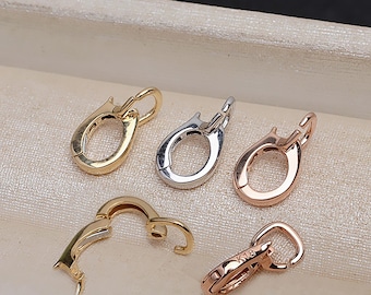 May include: Five metal jewelry clasps in gold, silver, and rose gold. The clasps are oval-shaped with a hinged design for secure closure. One clasp is marked "K18". These findings are used for necklaces and bracelets.