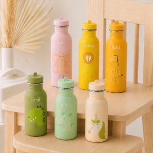 Op de afbeelding: Zes cilindervormige metalen drinkflessen in diverse pastel- en felle kleuren, elk voorzien van een unieke dierenillustratie en een gepersonaliseerde naam. De flessen tonen een roze vlinder, gele leeuw, oranje giraf, groene dinosaurus, lichtgroene draak en een crèmekleurige eenhoorn.