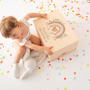 May include: A wooden keepsake box with a rainbow and heart design. The box is personalized with the name "Matilda" and the text "Our First Memories 2023".