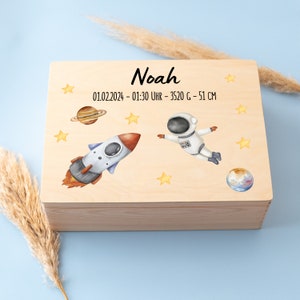 Peut inclure: Une boîte à souvenirs en bois sur le thème de l'espace. Le couvercle présente une fusée, un astronaute, des étoiles et des planètes. La boîte est personnalisée avec le nom "Noah" et la date "01.02.2024 - 01:30 UHR - 3520 G - 51 CM".