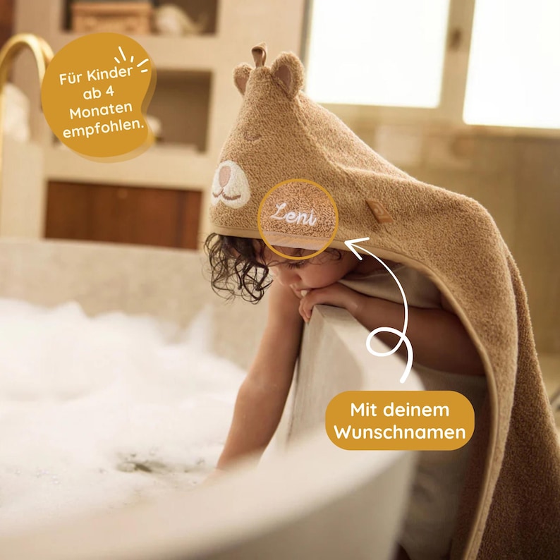 May include: A brown hooded towel with a bear face and the name "Leni" embroidered on it. The towel is being worn by a child in a bathtub. The text "F&uuml;r Kinder ab 4 Monaten empfohlen." is visible in the top left corner of the image. The text "Mit deinem Wunschnamen" is visible in the bottom right corner of the image.