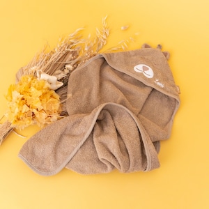 May include: A brown hooded towel with a cute bear face embroidered on the hood. The towel is made of soft, absorbent material and is perfect for drying a baby after bath time.