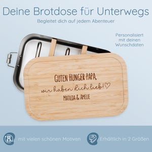 May include: A stainless steel and bamboo lunchbox. The bamboo lid is engraved with the text "GUTEN HUNGER PAPA, wir haben dich lieb!♡ MATILDA & AMELIE". The lunchbox is designed for on-the-go use and is available in two sizes.