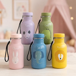 Könnte beinhalten: Fünf bunte Metalltrinkflaschen mit schwarzen Trageschlaufen. Die Flaschen zeigen Tierillustrationen und Namen: eine rosa Flasche mit einem Hasen namens Clara, eine lila Flasche mit einer Maus namens Fiona, eine grüne mit einem Dinosaurier namens Emil, eine blaue mit einem Elefanten namens Jakob und eine gelbe mit einem Löwen namens Matteo.