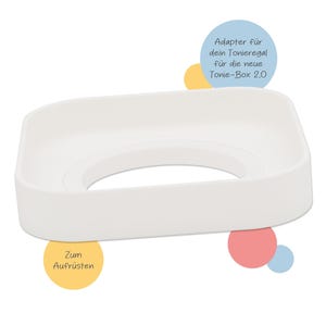 Könnte beinhalten: Ein weißer, rechteckiger Adapter mit einem kreisförmigen Ausschnitt in der Mitte. Der Text auf dem Bild lautet "Adapter für dein Tonie Regal für die neue Tonie-Box 2.0" und "Zum Aufrüsten".