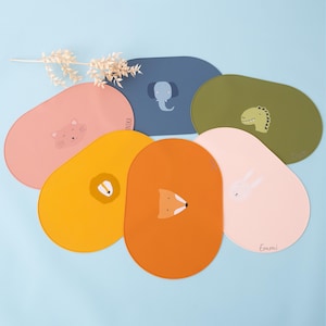 Può includere: Set di sei tovagliette individuali in silicone colorate con illustrazioni di animali. Ogni tovaglietta presenta un animale diverso, tra cui un gatto, un leone, una volpe, un coniglio, un elefante e un dinosauro. Le tovagliette sono di forma ovale e hanno una superficie testurizzata.