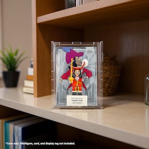 May include: A clear acrylic display case featuring a Captain Hook Lego minifigure. The minifigure is in a red coat, black pants, and a white wig. The case has the text "CMF Disney Series 1 Captain Hook".