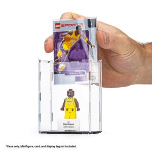 May include: A clear acrylic display case holding a Kobe Bryant Lego minifigure and a basketball card. The card features a photo of Kobe Bryant in a Lakers uniform. The Lego figure is yellow and black, with the name "Kobe Bryant" on the base.
