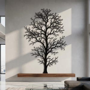 May include: A large, black, flat metal wall art piece shaped like a leafless tree with intricate, spreading branches. The silhouette of the tree is mounted vertically on a light-colored wall, extending from a wooden shelf toward the ceiling.