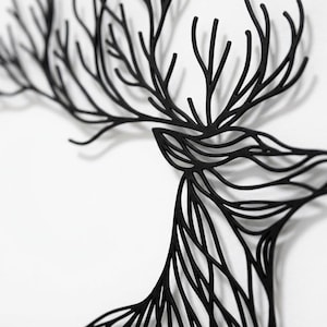 May include: Black deer head wall art with intricate, branch-like antlers and a detailed profile. The artwork is made of a solid black material and is mounted on a white background, creating a striking contrast. A decorative piece for home decor.