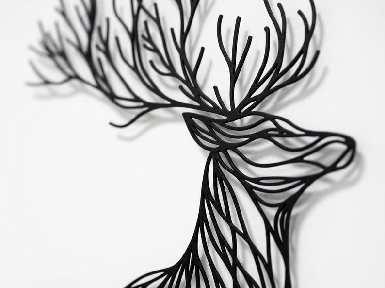 May include: Black deer head wall art with intricate, branch-like antlers and a detailed profile. The artwork is made of a solid black material and is mounted on a white background, creating a striking contrast. A decorative piece for home decor.