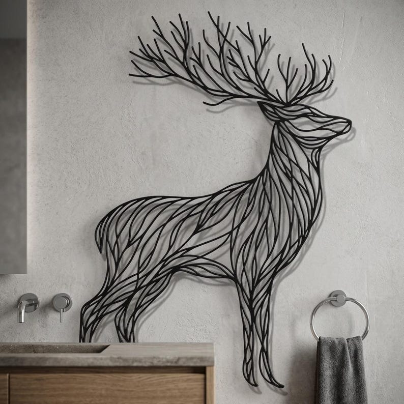 May include: Black metal deer wall art. The deer is depicted in a stylized, linear design, with intricate details forming the body and antlers. The artwork is mounted on a light gray wall, adding a modern touch to the space.