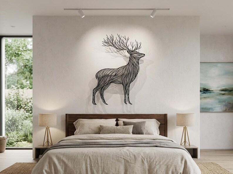 May include: A black metal deer wall art decorates a bedroom wall above a bed with neutral-toned bedding. The deer sculpture has detailed lines and large antlers. Two lamps with gold bases sit on either side of the bed.