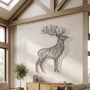 May include: A black metal deer wall art sculpture. The deer is depicted in a linear style with intricate details, mounted on a neutral-colored wall. The sculpture casts a shadow, enhancing the three-dimensional effect. The artwork adds a touch of nature-inspired decor.