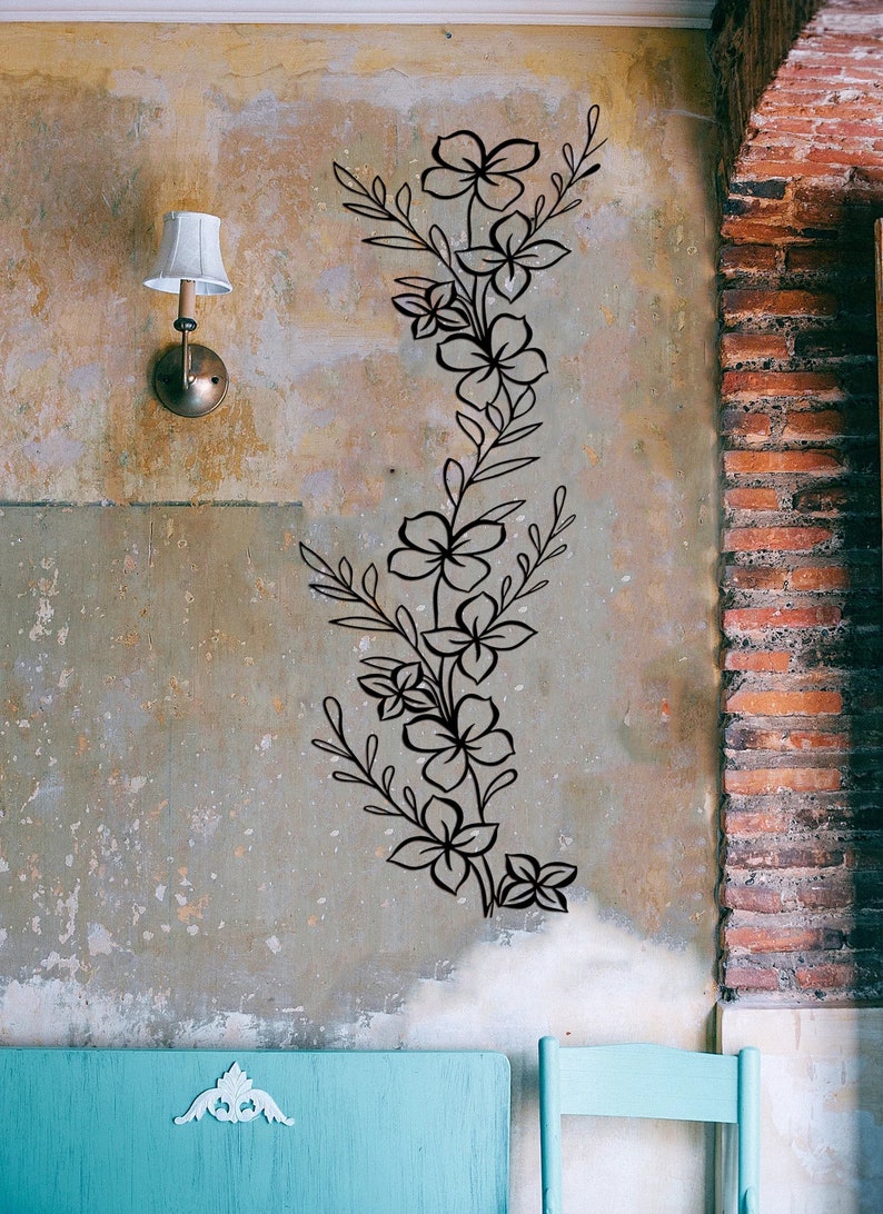 Puede incluir: Pegatina de pared floral negra con un dise&ntilde;o de vid, con m&uacute;ltiples flores y hojas. La pegatina se aplica a una pared texturizada de color marr&oacute;n claro.
