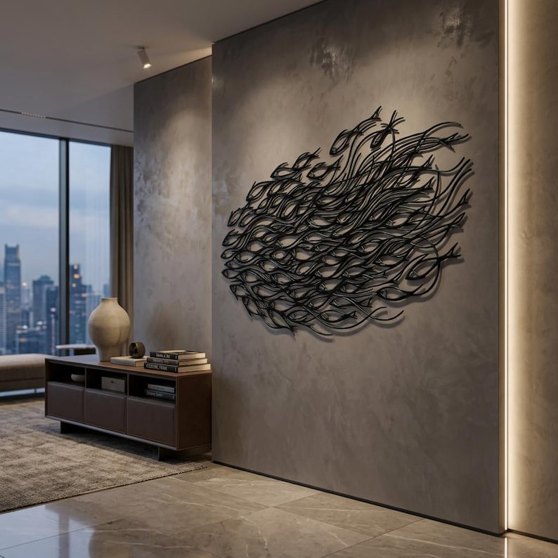 May include: A large black metal wall sculpture depicting a dense school of fish swimming in a unified direction. The artwork features intricate, flowing wire-like silhouettes of numerous fish arranged in an oval formation on a gray wall.