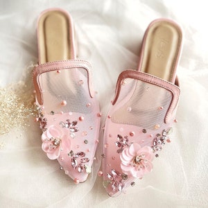 May include: A pair of pink mesh slip-on shoes with delicate floral embellishments and rhinestones.