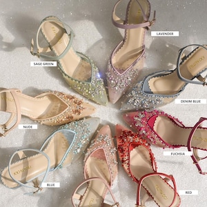 May include: A collection of ten pairs of women's shoes featuring jeweled embellishments. The shoes are made from a sheer fabric with a pointed toe and a delicate ankle strap. The shoes are available in a range of colours, including sage green, lavender, denim blue, nude, blue, fuchsia, red, and rose gold.