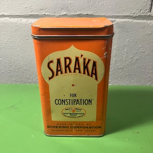 May include: Vintage orange metal tin with the word "SARAKA" in a stylized font. The tin reads "FOR CONSTIPATION" and "MADE IN U.S.A. BY SCHERING CORPORATION, BLOOMFIELD, NEW JERSEY."