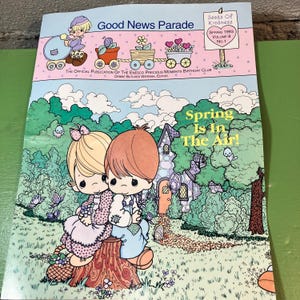 May include: A vintage "Good News Parade" magazine cover with the text "Spring Is In The Air!" features cartoon illustrations of children and a whimsical landscape. The cover includes the text "Seeds of Kindness" and "Spring 1993 Volume 8 No. 1".